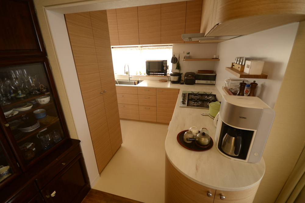 タモ柾目とコーリアンのアール扉のあるL型キッチン